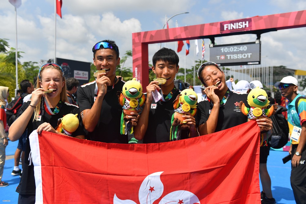 Bailee holding the gold medal with other HK team members